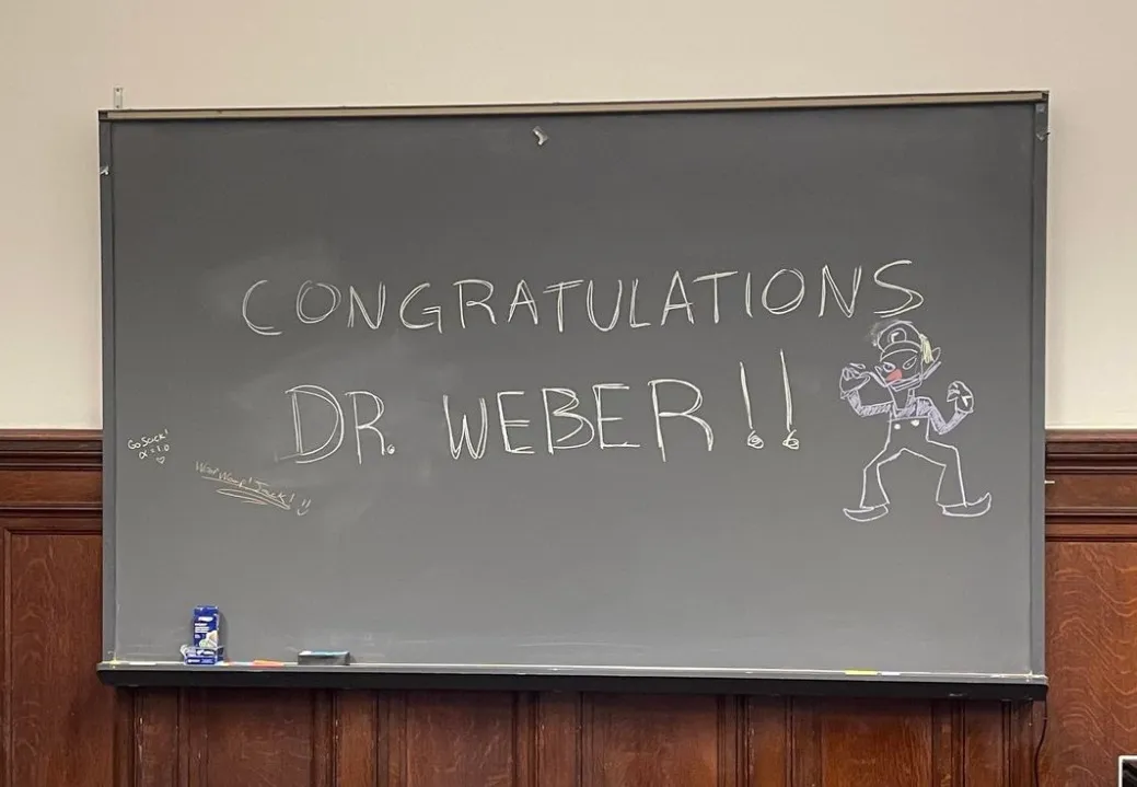 Chalkboard with "Congratulations Dr Weber" written and Waluigi drawn.